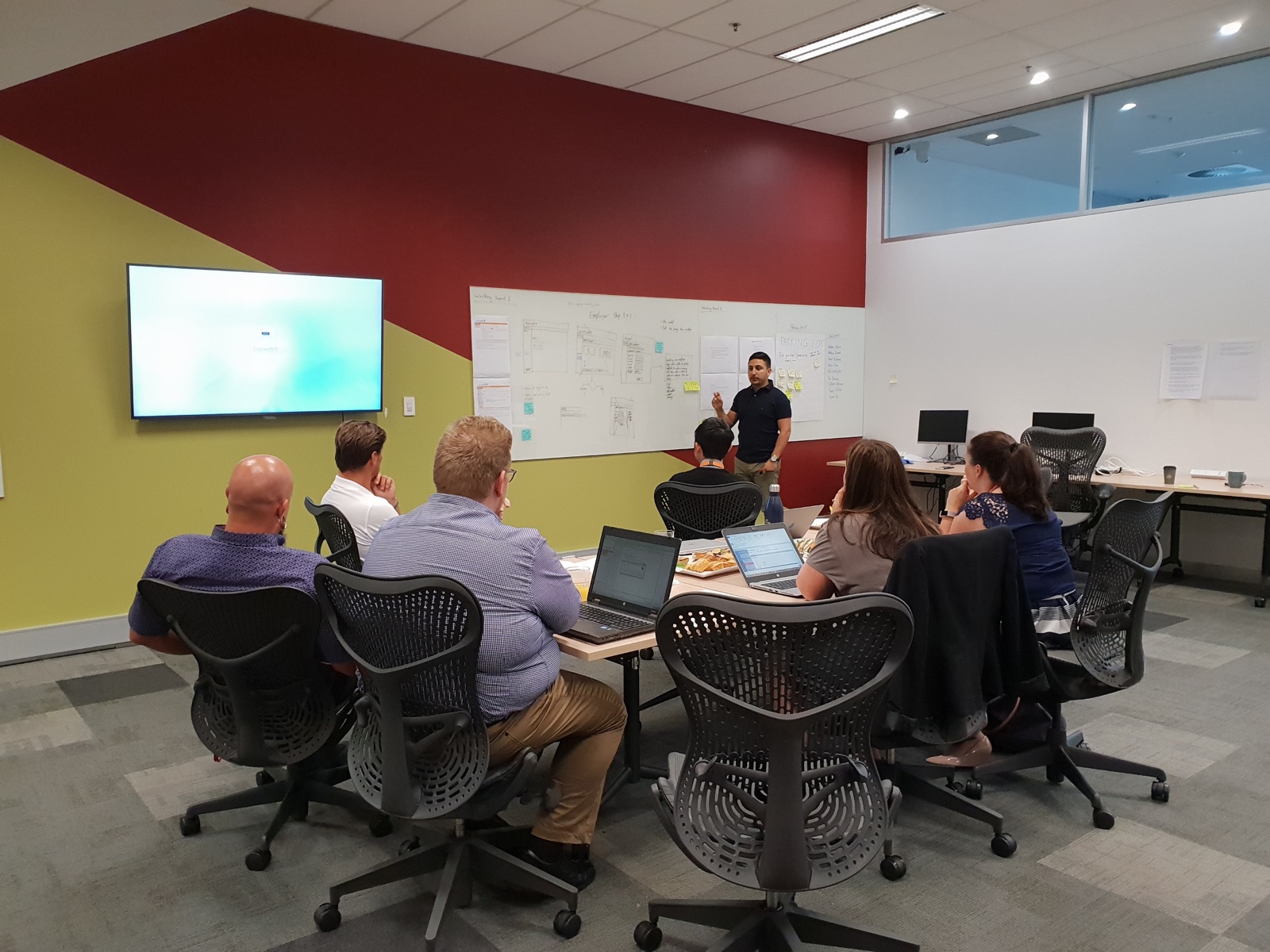 Anthony facilitating a workshop with colleagues at AustralianSuper in front of whiteboards covered in sketches and notes.