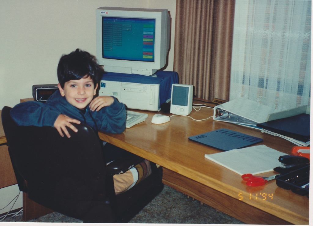 Anthony as a child sitting beside a desktop computer.
